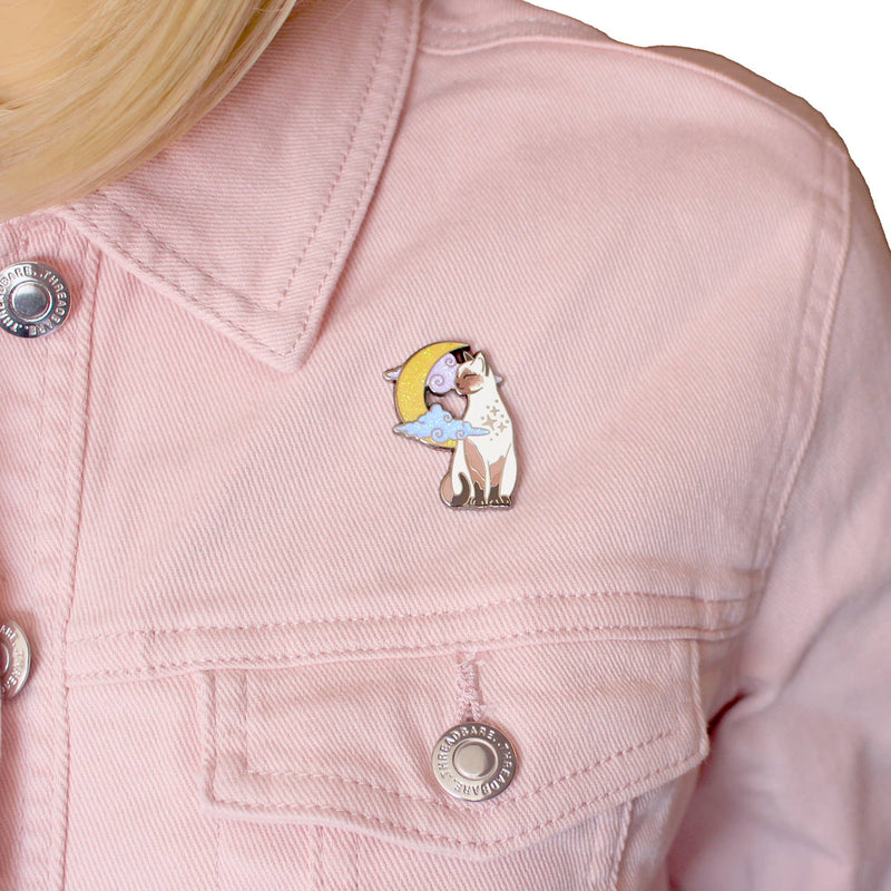 Pin's Glitter Punk chat siamois assis devant une lune scintillante et des nuages pastel
