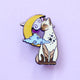 Pin's Glitter Punk chat siamois assis devant une lune scintillante et des nuages pastel