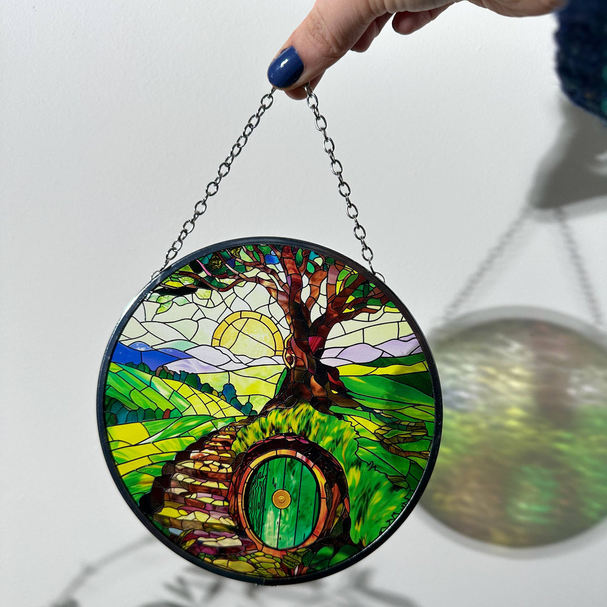 Attrape-soleil en verre effet vitrail inspiré de la Comté, chemin vers une maison à porte ronde
