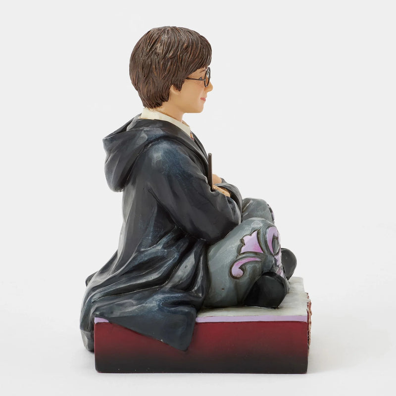 Figurine Harry Potter by Jim Shore, Harry assis par terre en robe de Poudlard tenant sa baguette