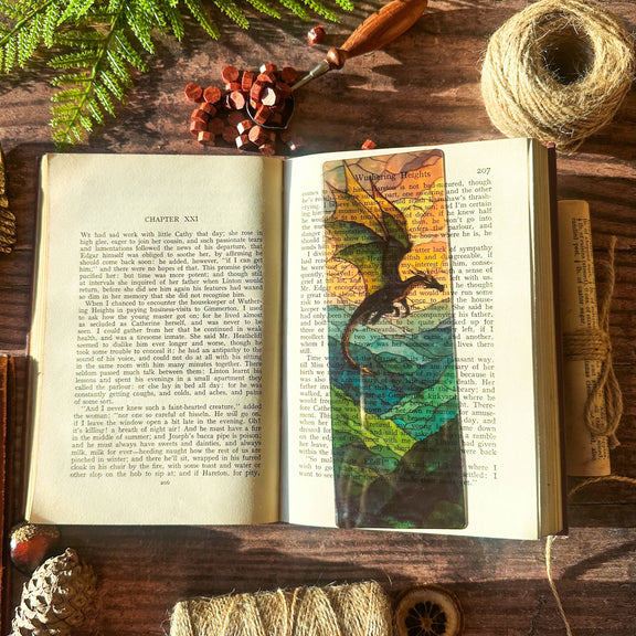 Marque-page transparent effet vitrail avec un dragon dominant un paysage montagneux