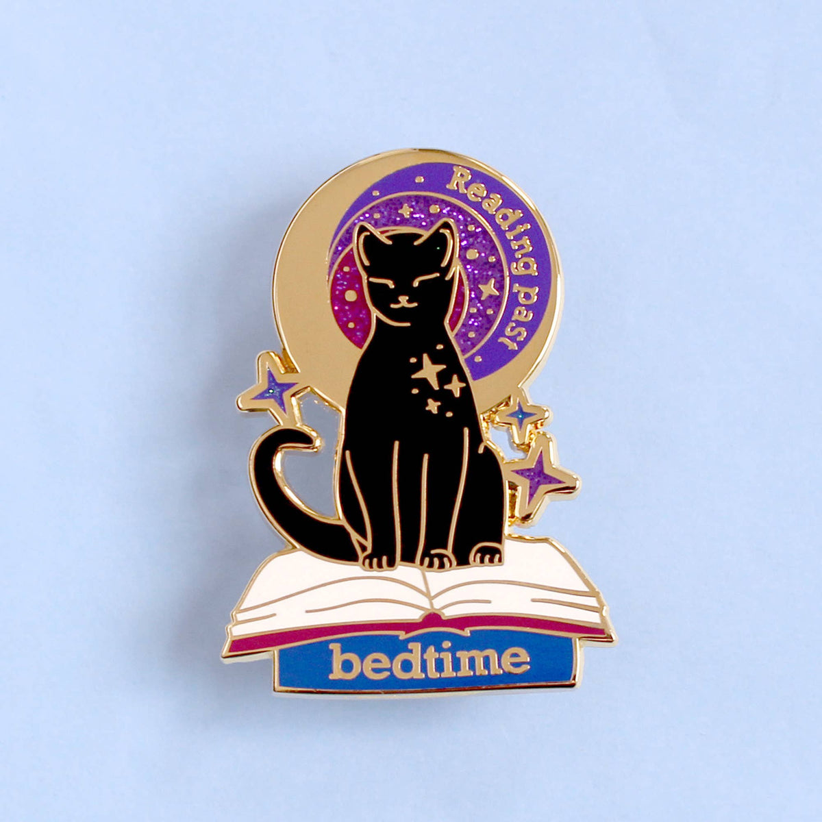 Pin's Glitter Punk Reading past bedtime, chat noir assis sur un livre ouvert sous un ciel étoilé