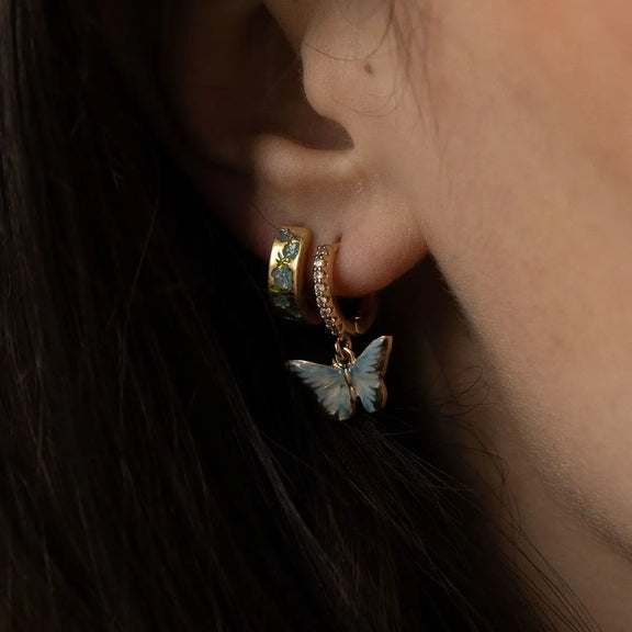 Boucles d'oreilles huggie dorées Fable England, charm papillon bleu émaillé à la main et zircones