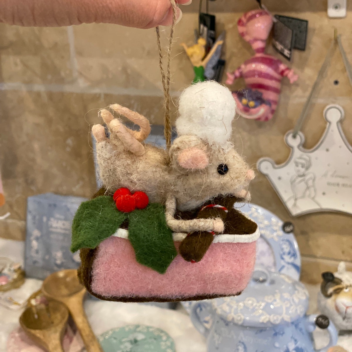 Souris pâtissière en laine feutrée à suspendre, posée sur une part de gâteau rose avec houx