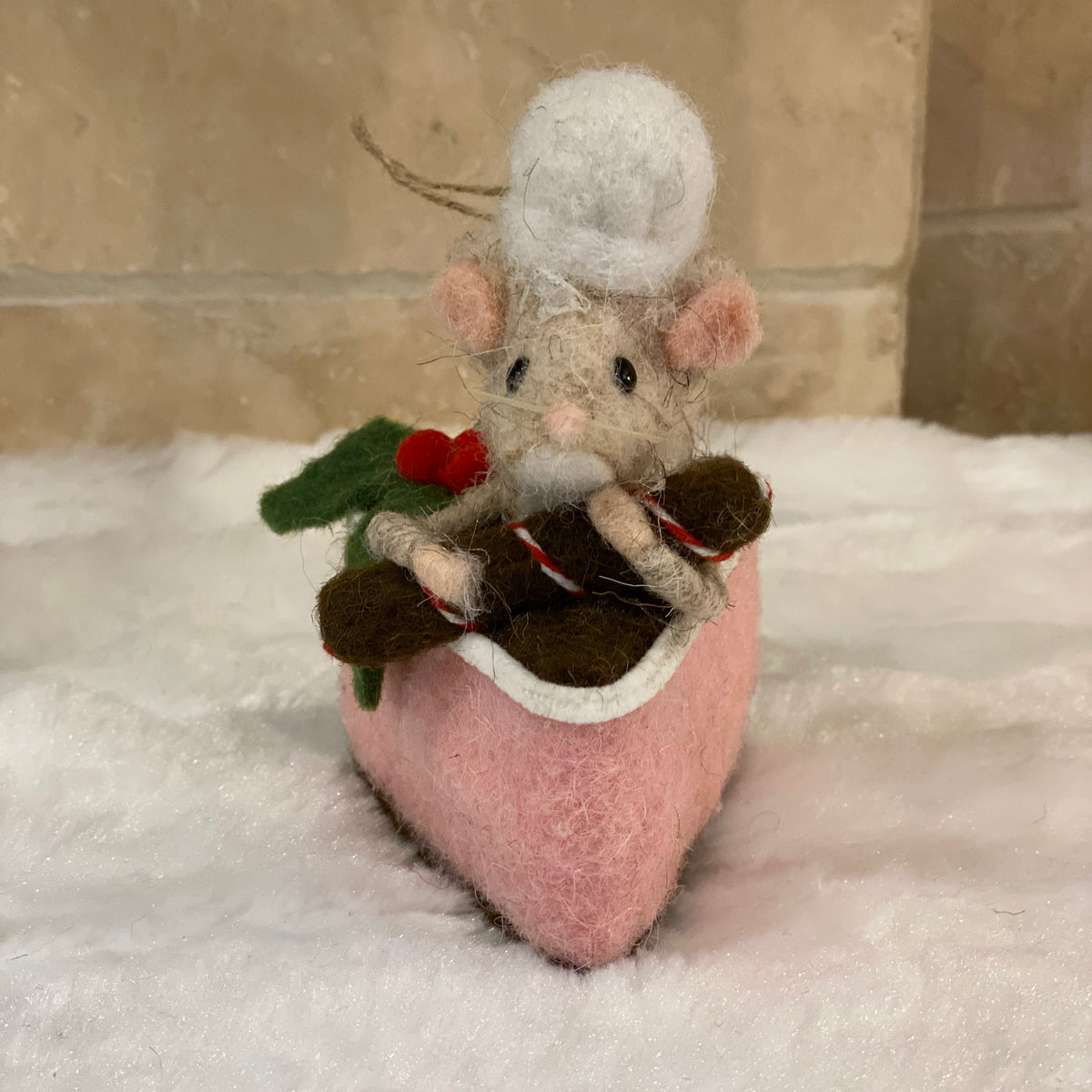 Souris pâtissière en laine feutrée à suspendre, posée sur une part de gâteau rose avec houx