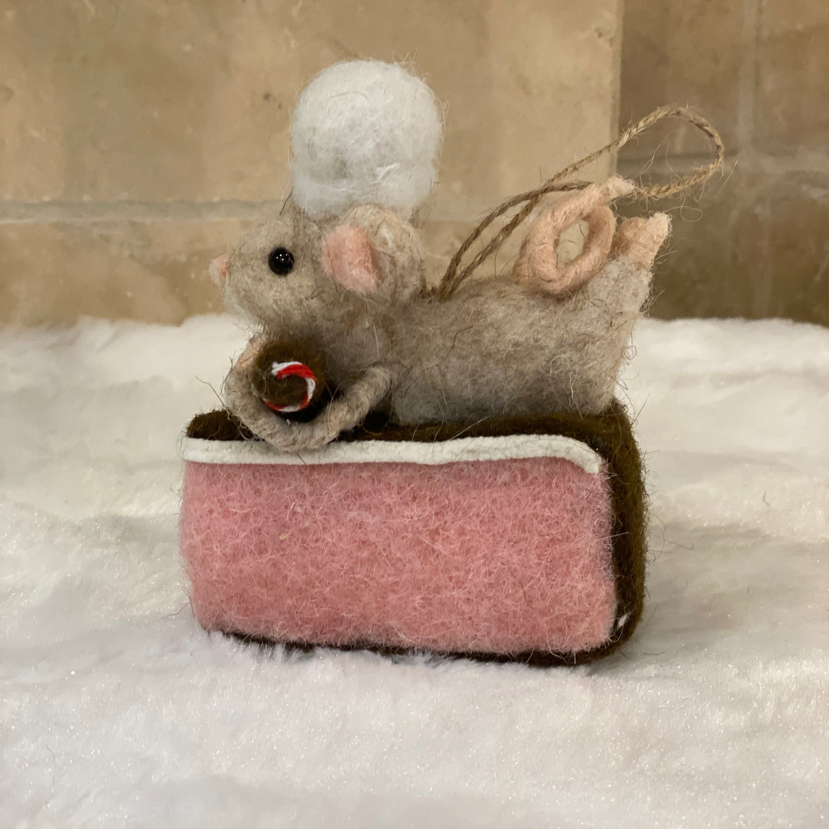 Souris pâtissière en laine feutrée à suspendre, posée sur une part de gâteau rose avec houx