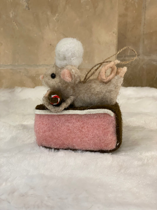 Souris pâtissière en laine feutrée à suspendre, posée sur une part de gâteau rose avec houx