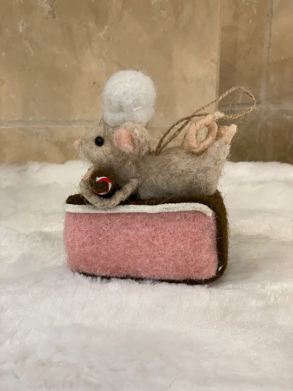 Souris pâtissière en laine feutrée à suspendre, posée sur une part de gâteau rose avec houx