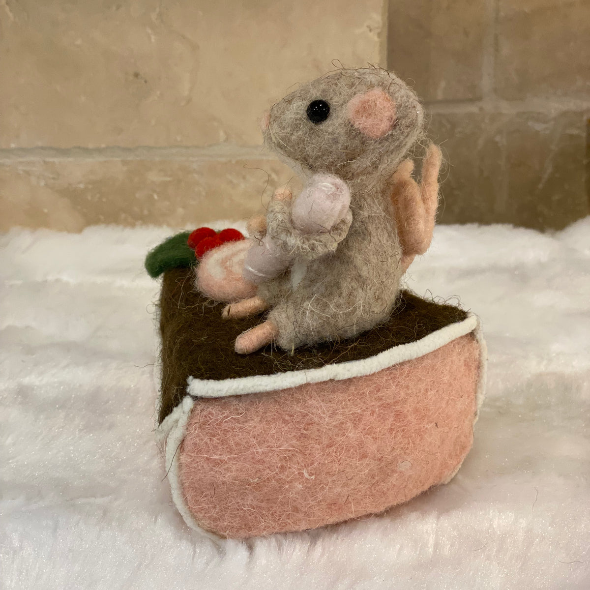 Figurine de Noël en laine feutrée, souris assise sur une part de gâteau avec houx et glaçage
