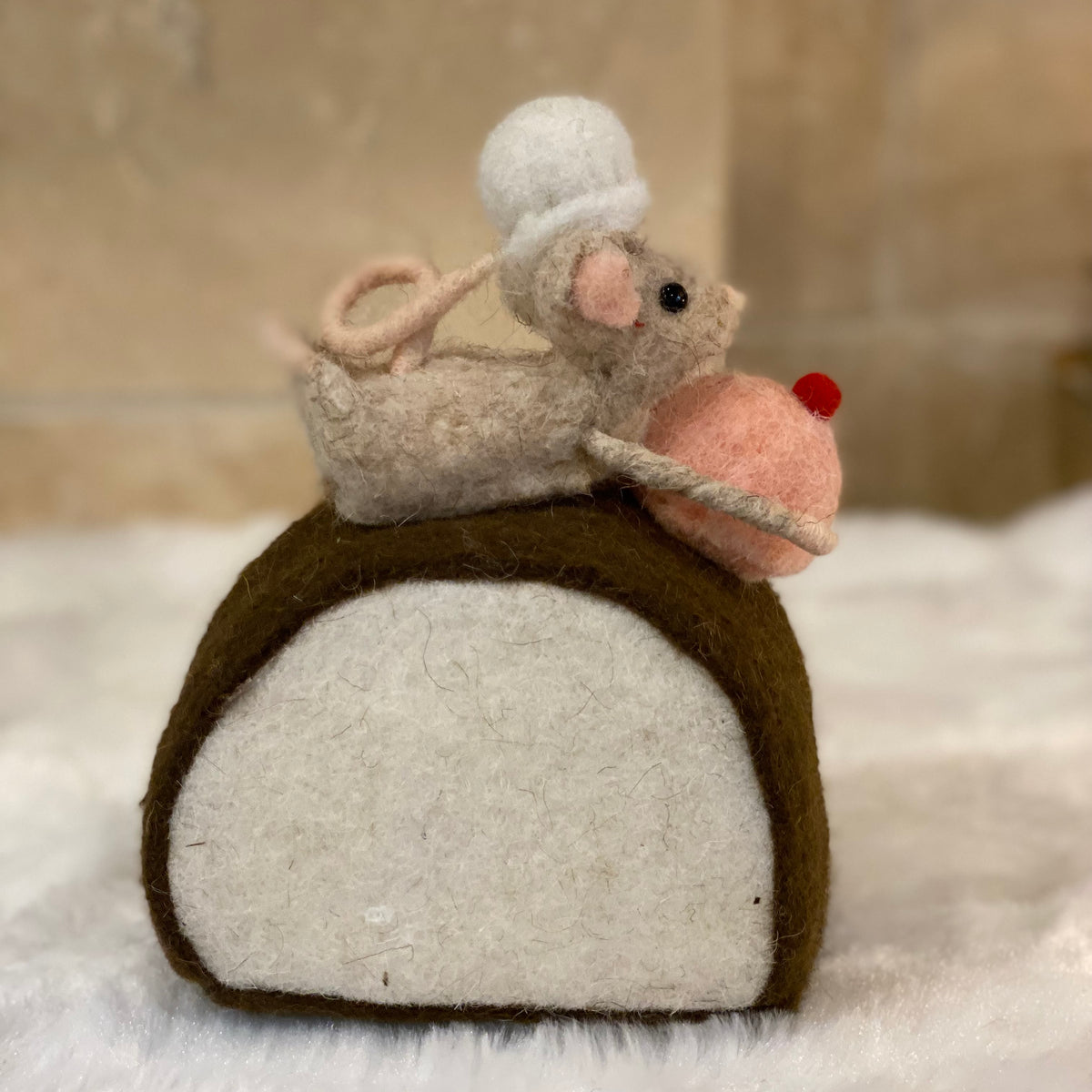 Figurine de Noël en laine feutrée, souris à toque blanche assise sur une bûche pâtissière