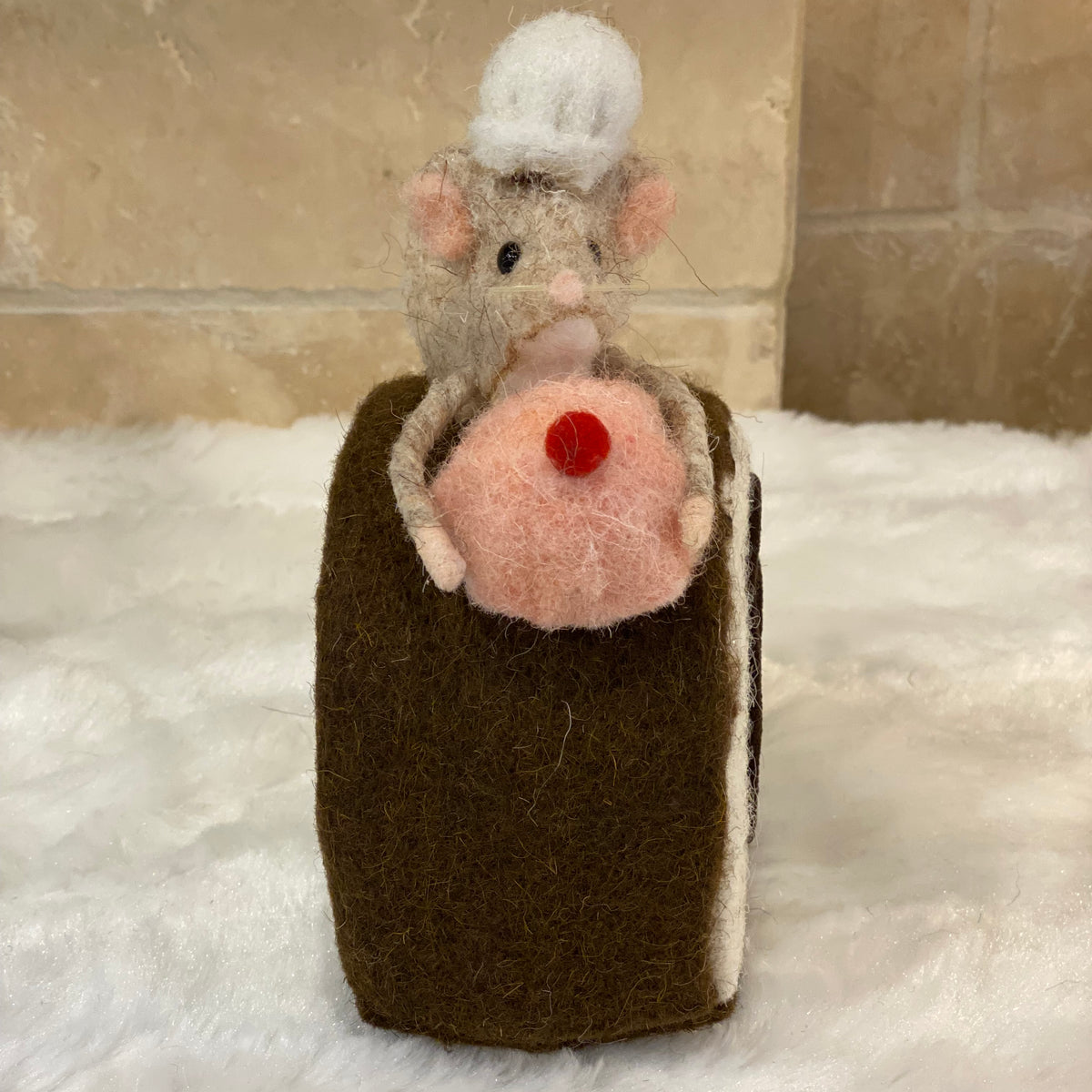 Figurine de Noël en laine feutrée, souris à toque blanche assise sur une bûche pâtissière