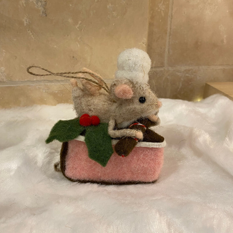 Souris pâtissière en laine feutrée à suspendre, posée sur une part de gâteau rose avec houx
