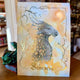 Illustration fantasy du dragon Sèmevent aux finitions dorées, crayons et aquarelle, L'Or.angerie