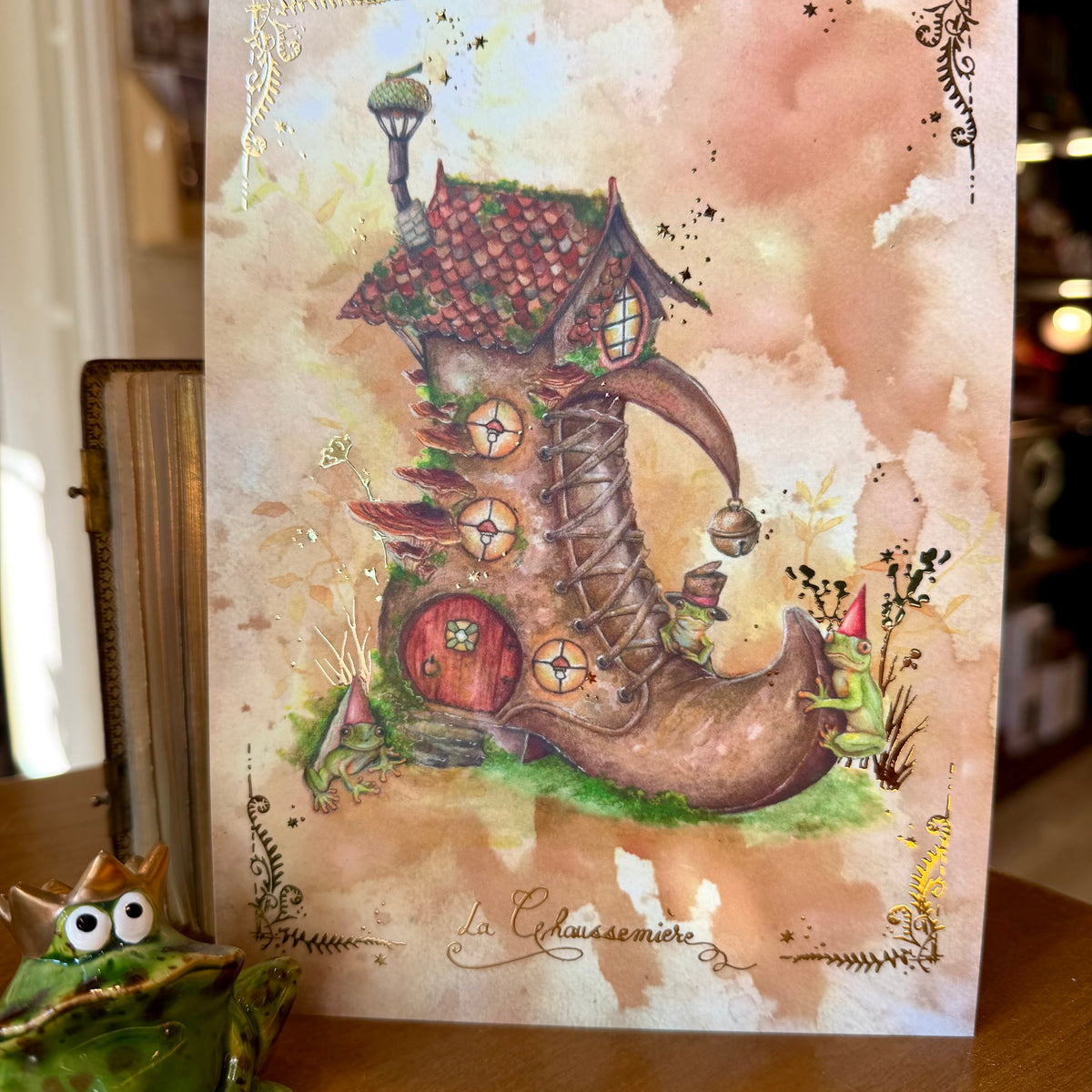 Illustration La Chaussemière, maison féerique en forme de chaussure avec trois grenouilles