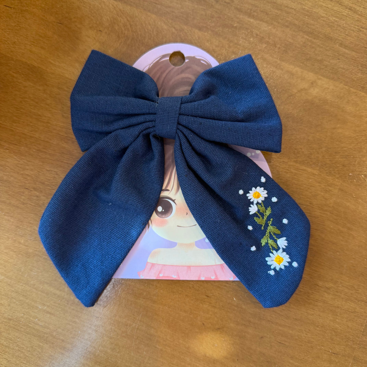 Pince à cheveux nœud en tissu bleu profond décorée de petites fleurs brodées multicolores