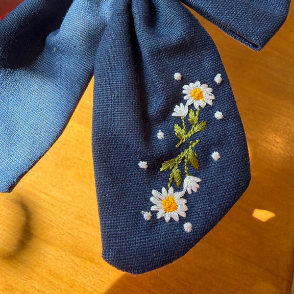 Pince à cheveux nœud en tissu bleu profond décorée de petites fleurs brodées multicolores