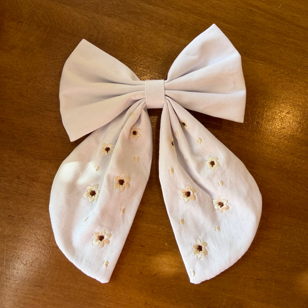 Pince à cheveux nœud en tissu blanc lumineux ornée de petites broderies florales ton sur ton