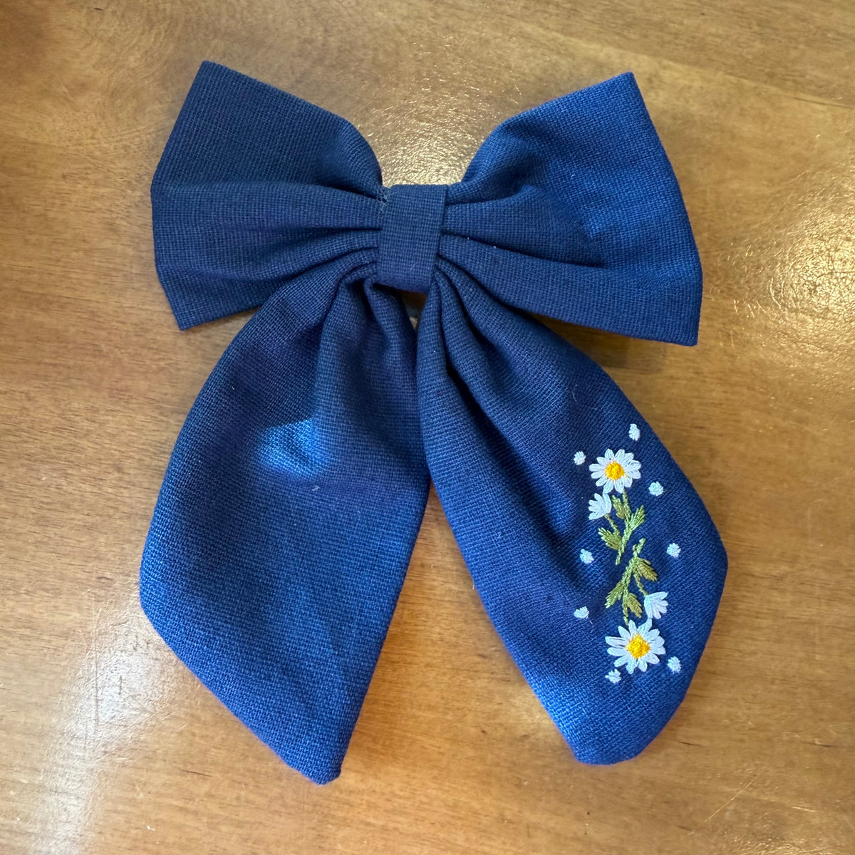Pince à cheveux nœud en tissu bleu profond décorée de petites fleurs brodées multicolores
