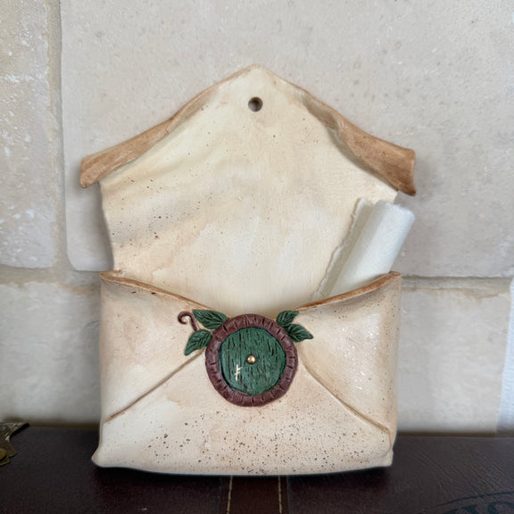 Enveloppe murale artisanale en argile effet vieux parchemin ornée d'une petite porte ronde de maison hobbit