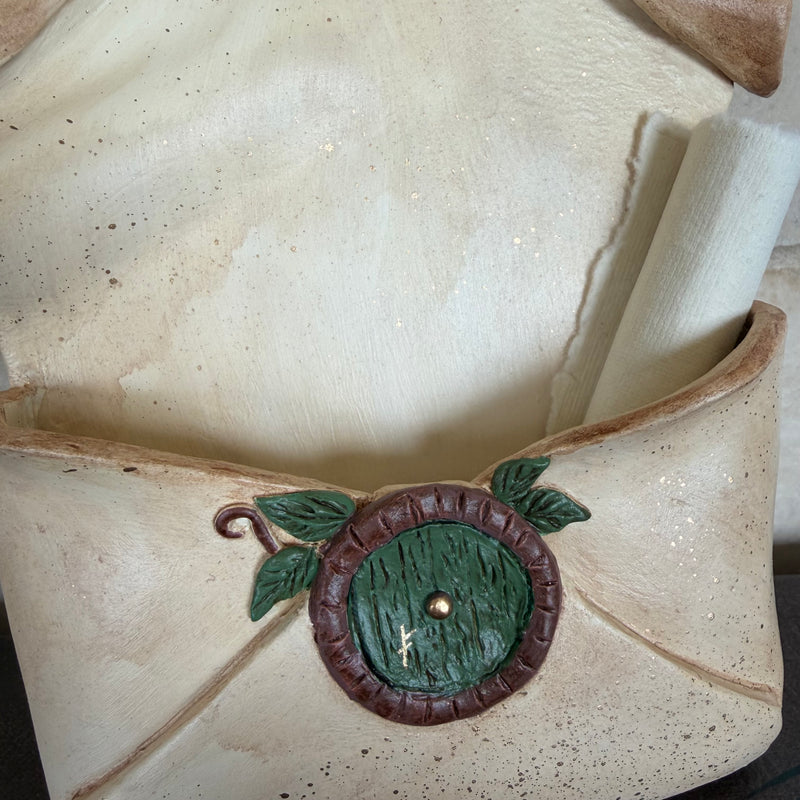 Enveloppe murale artisanale en argile effet vieux parchemin ornée d'une petite porte ronde de maison hobbit