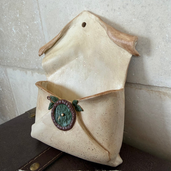 Enveloppe murale artisanale en argile effet vieux parchemin ornée d'une petite porte ronde de maison hobbit