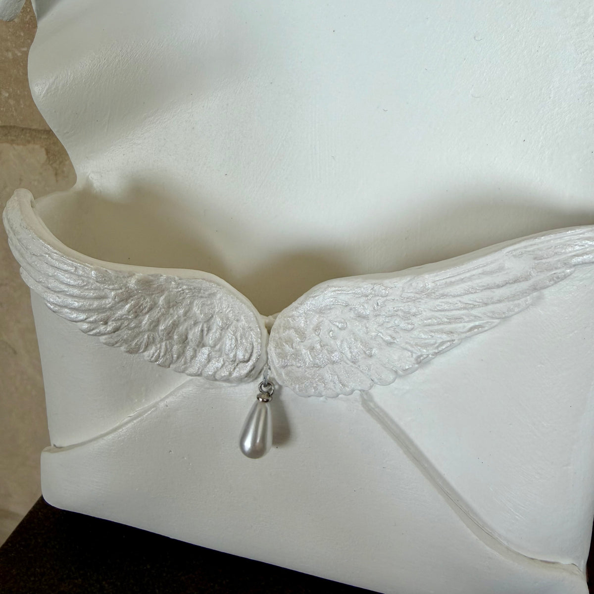 Enveloppe murale artisanale en argile ornée d'ailes d'ange irisées et d'une perle en forme de goutte