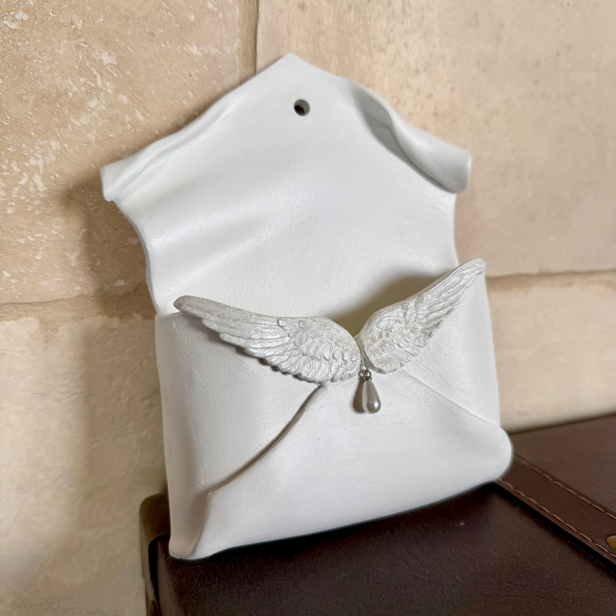 Enveloppe murale artisanale en argile ornée d'ailes d'ange irisées et d'une perle en forme de goutte