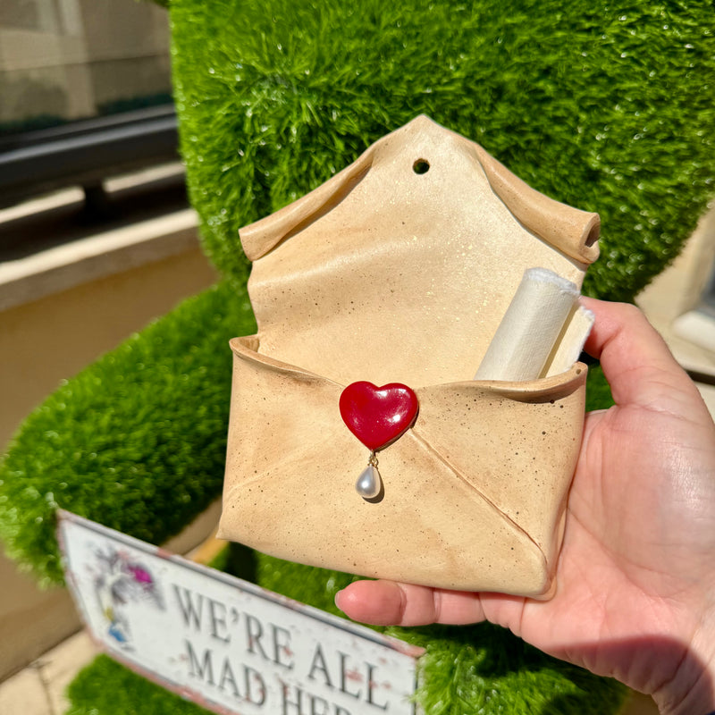 Enveloppe murale artisanale en argile effet parchemin ornée d'un cœur rouge brillant et d'une perle goutte