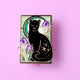 Pin's Glitter Punk Art Nouveau chat noir étoilé entouré de fleurs d'iris violettes sur fond vert