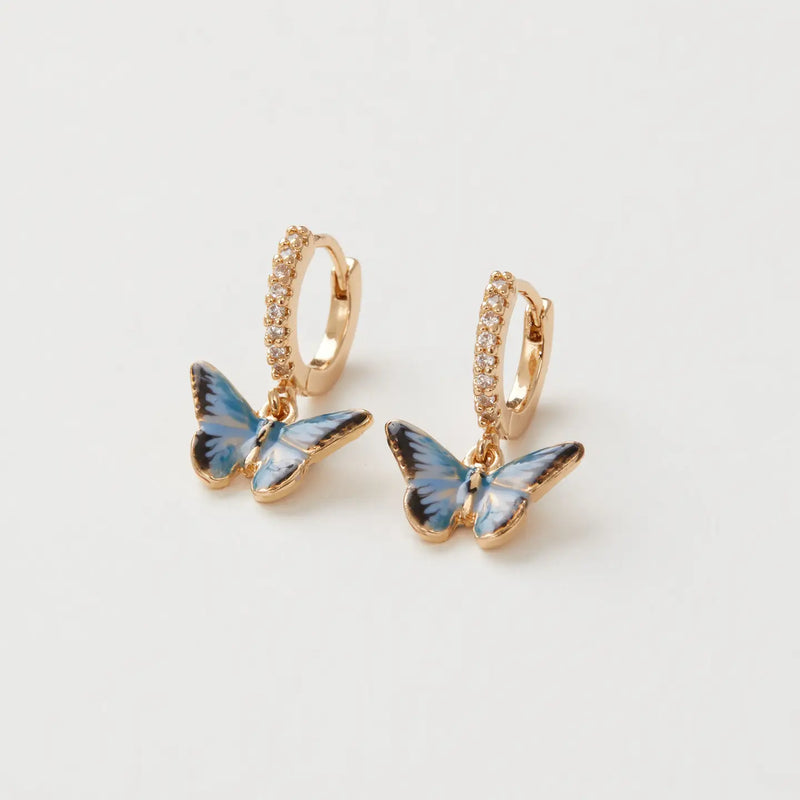 Boucles d'oreilles huggie dorées Fable England, charm papillon bleu émaillé à la main et zircones