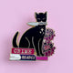 Pin's Glitter Punk Crime Reader, chat noir avec couteau assis sur une pile de polars et fleurs pourpres