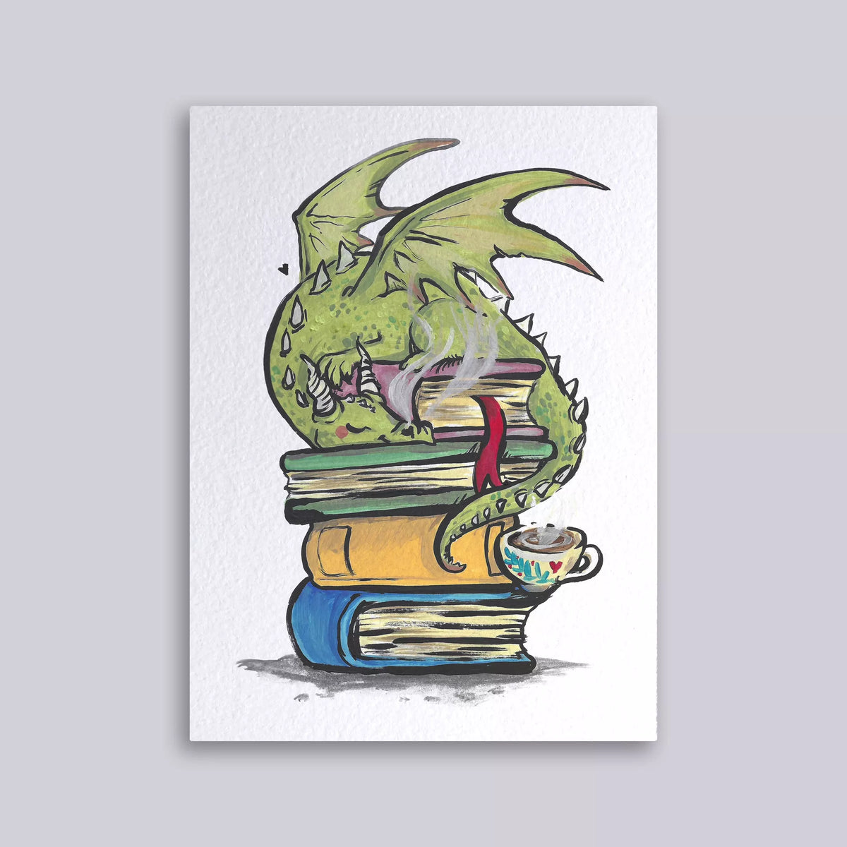 Carte postale illustrée d'un petit dragon vert endormi sur une pile de livres anciens avec une tasse de thé