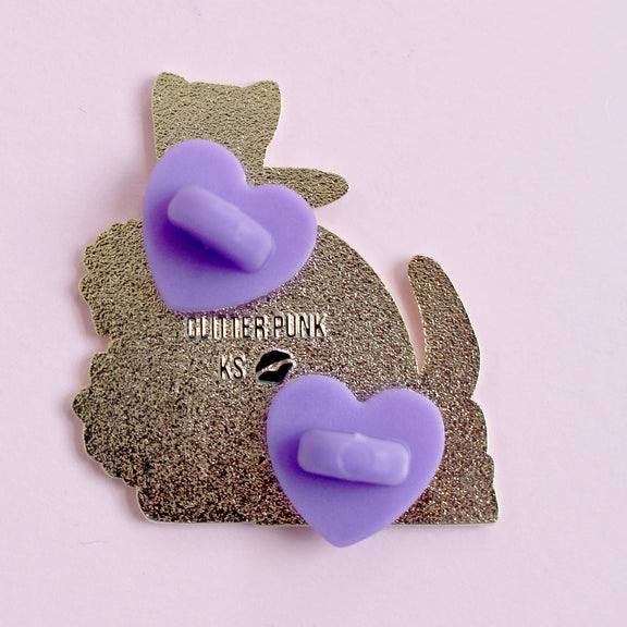 Pin's Glitter Punk Crime Reader, chat noir avec couteau assis sur une pile de polars et fleurs pourpres