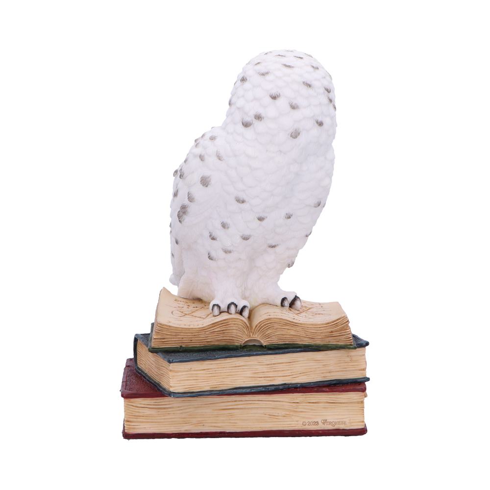Figurine chouette harfang des neiges blanche en résine perchée sur une pile de grimoires ouverts