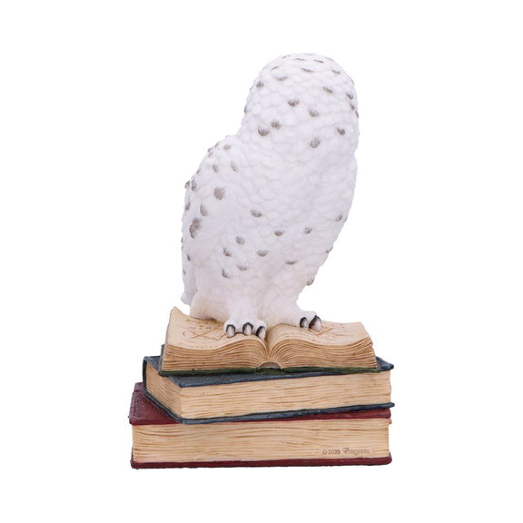 Figurine chouette harfang des neiges blanche en résine perchée sur une pile de grimoires ouverts