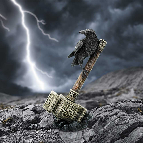 Figurine Nemesis Now d'un corbeau perché sur le marteau de Thor posé sur des rochers
