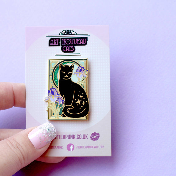 Pin's Glitter Punk Art Nouveau chat noir étoilé entouré de fleurs d'iris violettes sur fond vert