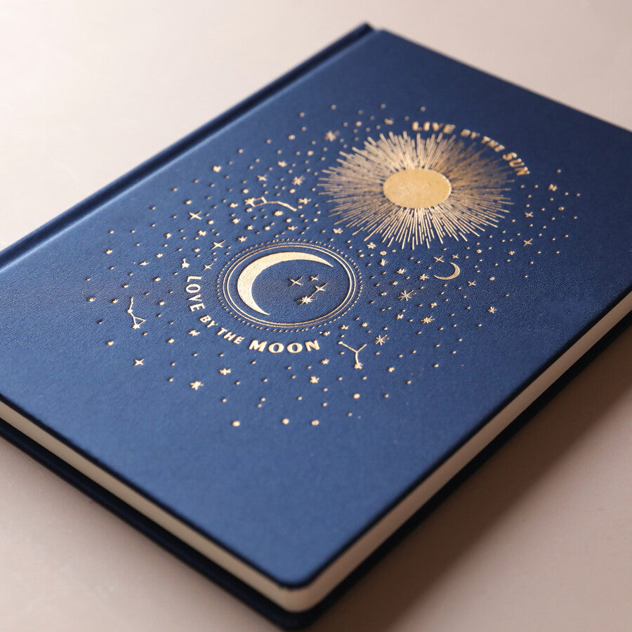 Carnet relié Live by the Sun Love by the Moon, couverture tissu bleu nuit à motifs célestes dorés