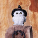 Statuette en résine d'une chouette blanche aux yeux dorés coiffée d'un grand chapeau de sorcière noir