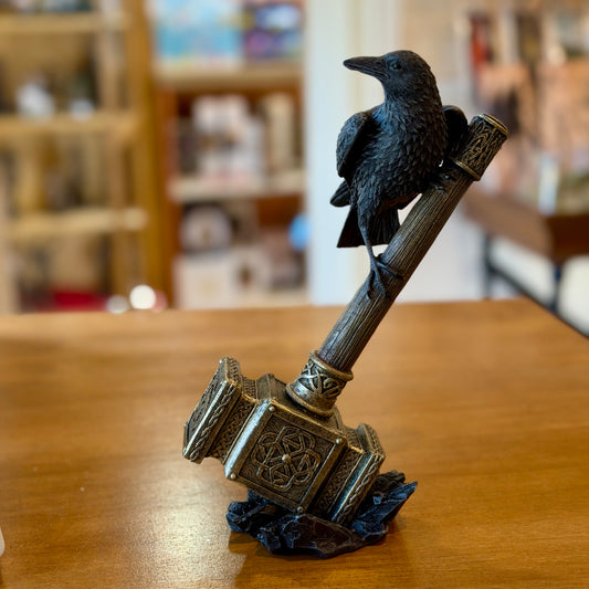 Figurine Nemesis Now d'un corbeau perché sur le marteau de Thor posé sur des rochers