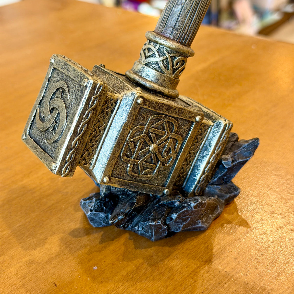 Figurine Nemesis Now d'un corbeau perché sur le marteau de Thor posé sur des rochers
