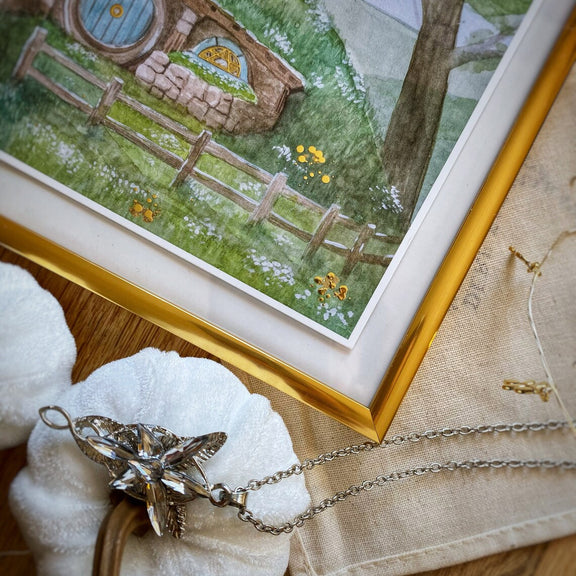 Illustration A5 d'une maison de hobbit à porte ronde et toit végétalisé nichée dans les collines verdoyantes