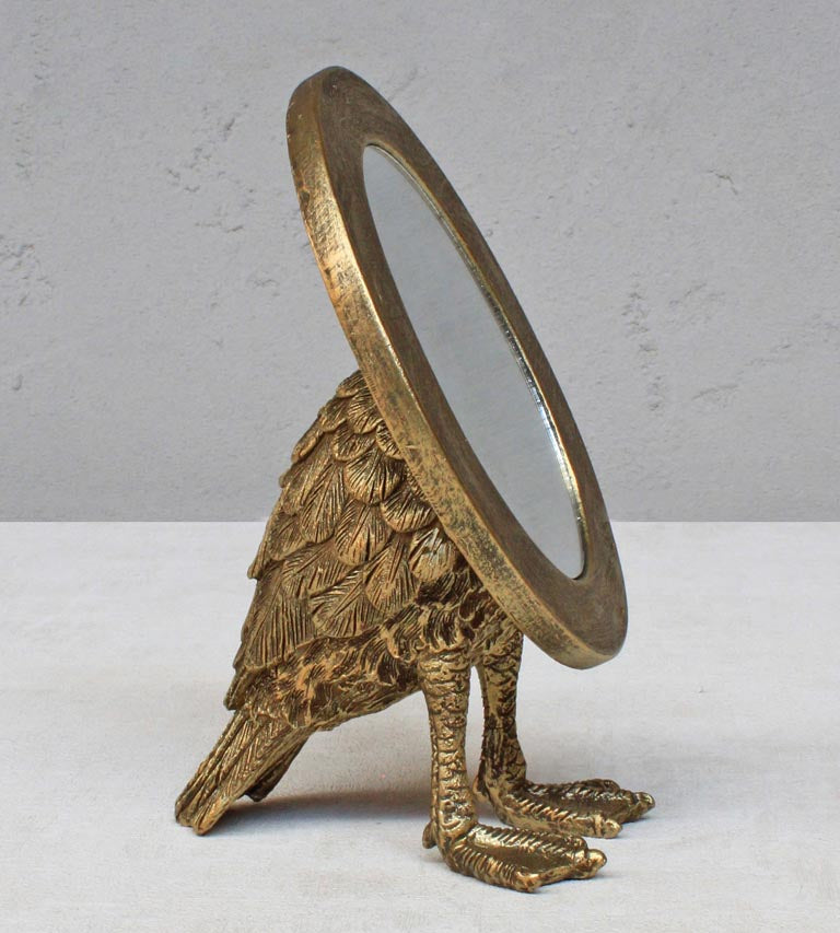 Miroir rond sur pied porté par un oiseau doré vieilli aux plumes texturées, esprit cabinet de curiosités