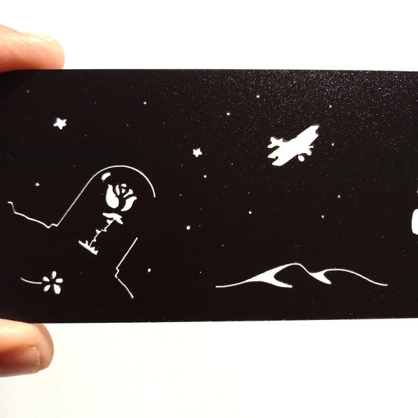 Marque-page découpé au laser en silhouette noire avec un jeune rêveur, un renard et un ciel étoilé