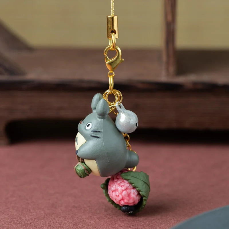Strap bijou de sac Totoro gris tenant un sakuramochi rose enveloppé d'une feuille de cerisier