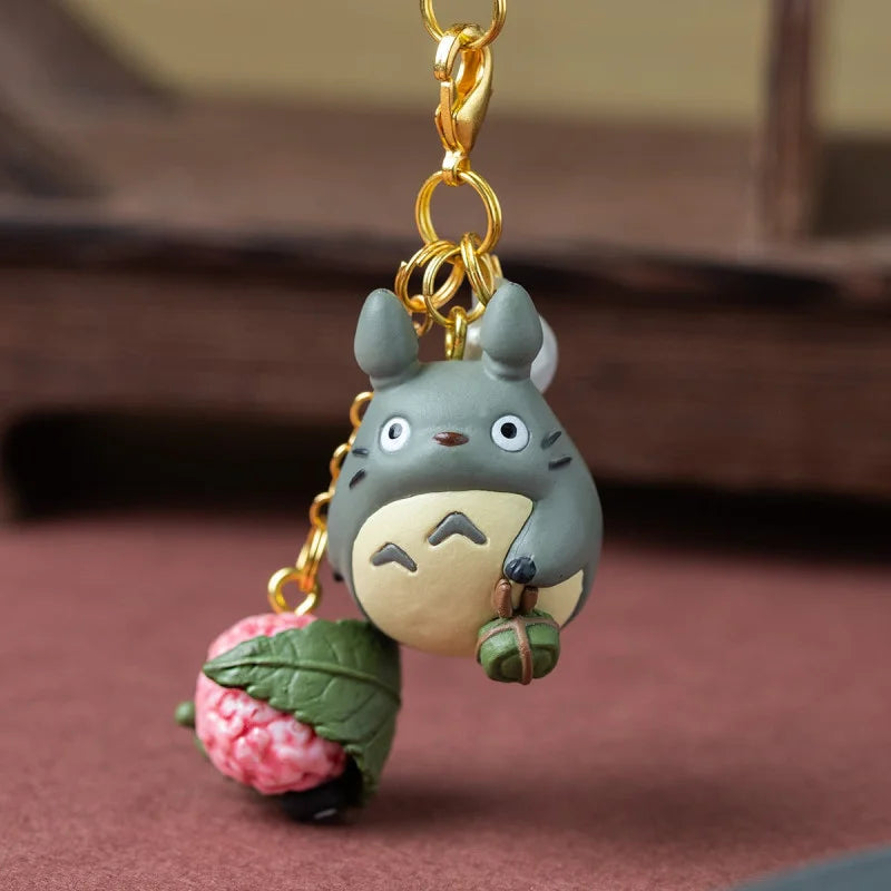 Strap bijou de sac Totoro gris tenant un sakuramochi rose enveloppé d'une feuille de cerisier