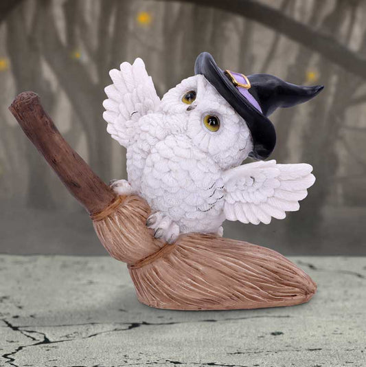 Figurine en résine d'une chouette blanche aux ailes déployées posée sur un balai volant